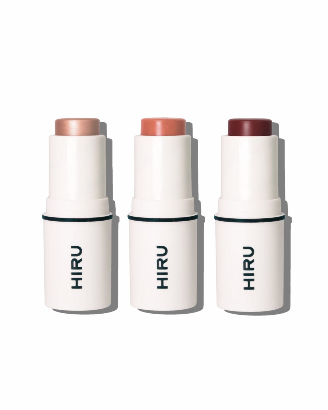 Three HIRU makeup sticks with different shades on a white background